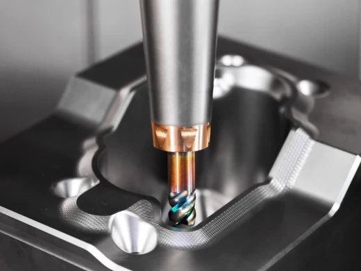 Der Schaftfräser von Pokolms großem Sortiment an Vollhartmetallfräsern, in in einer Aufnahme eingebaut und fährt zum fräsen in ein Bauteil rein.