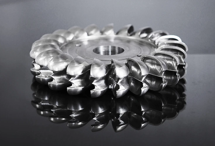 A milled Pelton wheel lying on a dark background