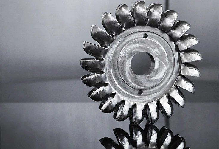 A milled Pelton wheel standing on a dark background