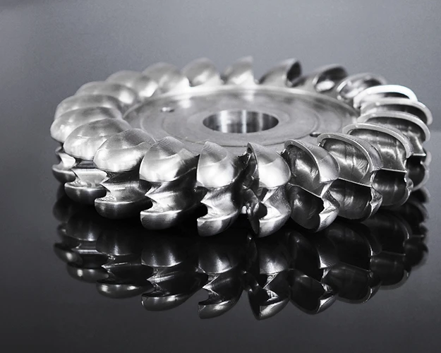 A milled Pelton wheel lying on a dark background