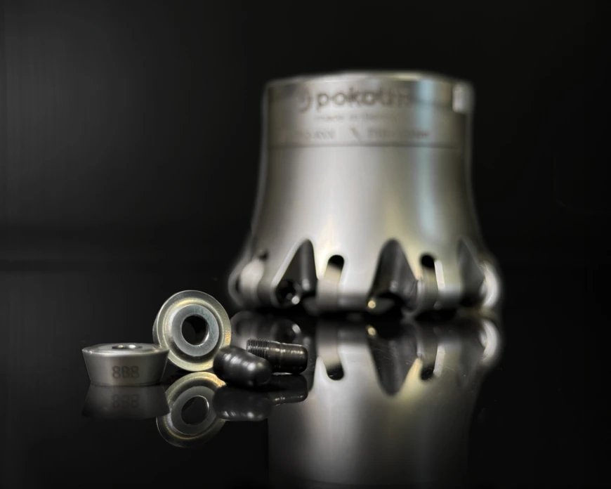 Spinworx round plates with pins in the foreground, a tool body in the background, all set against a dark background.